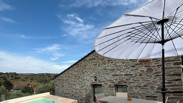 Un edificio de piedra con piscina y mobiliario de exterior.