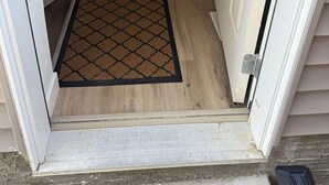 Una escalera de madera que lleva a una puerta blanca con felpudo.