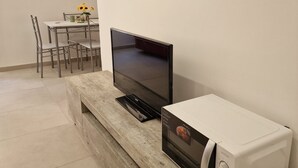 Une kitchenette équipée d’un four à micro-ondes, d’un téléviseur à écran plat et d’un coin repas avec une table et des chaises.