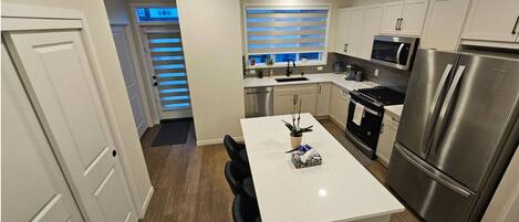 A modern kitchen with white cabinets, stainless steel appliances, and a central island.