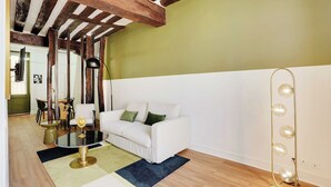 Ein Wohnzimmer mit einem weißen Sofa, einem runden Glastisch, einer schwarzen Stehlampe und einem hellen Boden.