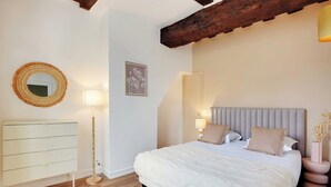 Ein Schlafzimmer mit einem Bett, Nachttischlampen, einem Schminktisch, einem Spiegel und einem gerahmten Bild an der Wand.
