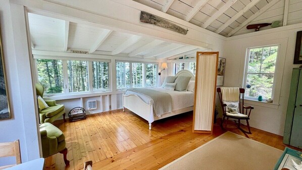 Une chambre à coucher avec un lit, une chaise, une fenêtre et une porte.