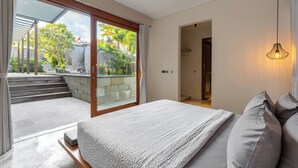 Ein Schlafzimmer mit einem großen Bett, Blick auf einen Garten durch eine Schiebetür und einer Treppe, die nach draußen führt.