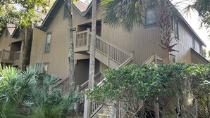 A multi-story building with a wooden exterior, a balcony on the second floor, and a staircase leading to the entrance. - One Block Kiawah Beach Villa (Kiawah Island)