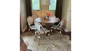 A dining area with a round table, four wicker chairs, a hanging lamp, and a view of greenery outside. - One Block Kiawah Beach Villa (Kiawah Island)