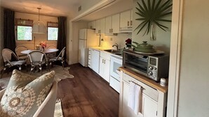 A cozy kitchen with white cabinets, a dining area with wicker chairs, and a large plant. - One Block Kiawah Beach Villa (Kiawah Island)