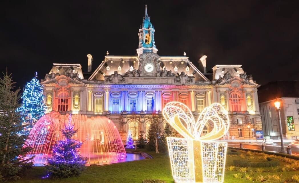 A historic building with a prominent tower and illuminated decorations, including a large book sculpture.