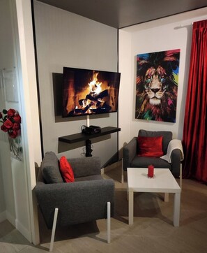 A modern living room with a flat-screen TV, two grey sofas with red cushions, a white coffee table, and a red curtain. - Beautiful apartment in Tours center, panoramic view of the city. (Tours)