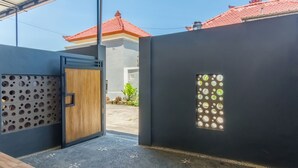 Een modern gebouw met een grijze gevel, een houten deur en een decoratief raam met ronde patronen.