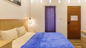 Een slaapkamer met een bed, een nachtkastje, een houten hoofdeinde, een hanglamp, een deur met een bord en een raam met gordijnen.