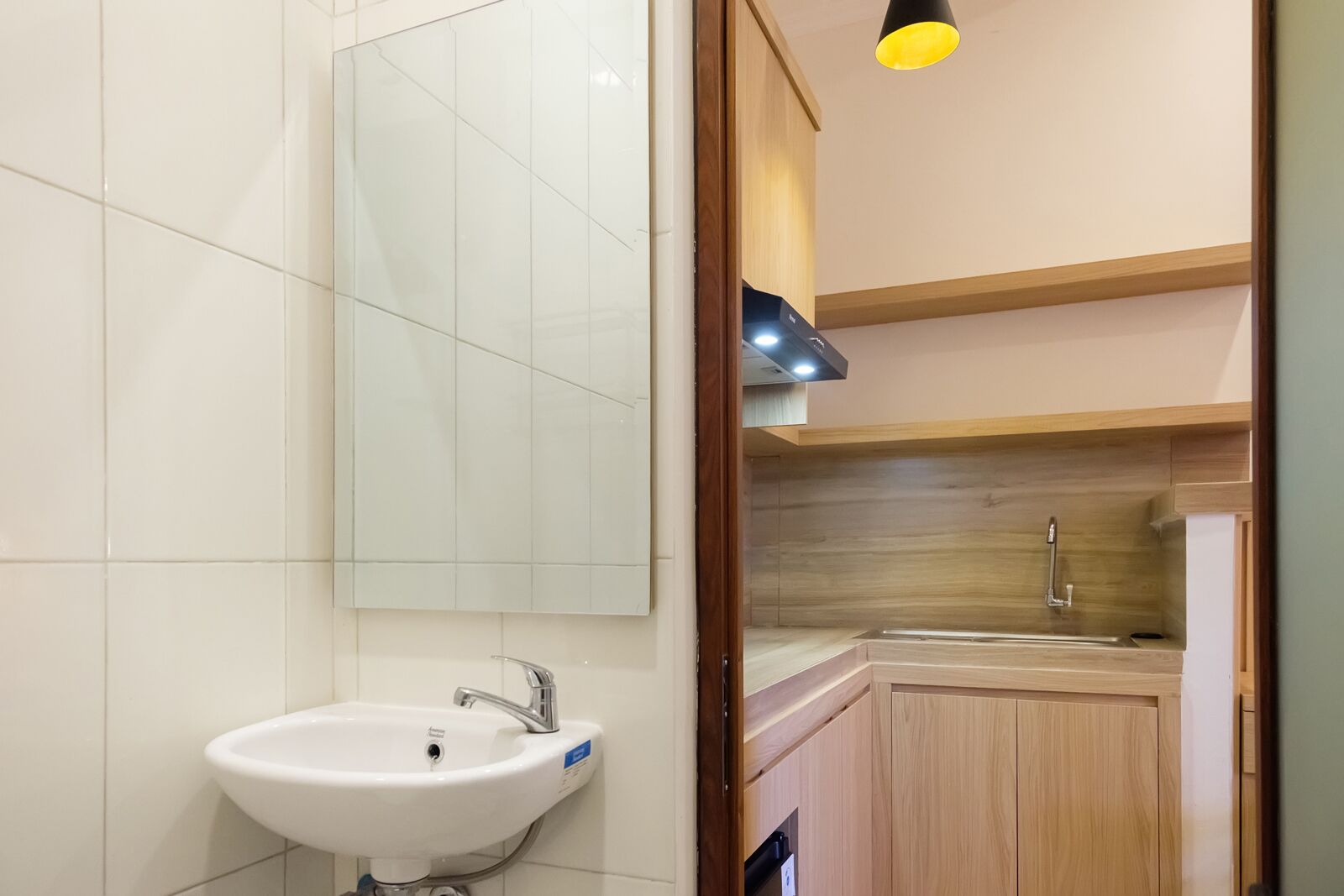 A modern bathroom with a white sink, mirror, and wooden cabinets.