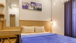 Hotelkamer met een bed, een bureau, een stoel, een wandairconditioner, een schilderij en een raam met gordijnen.