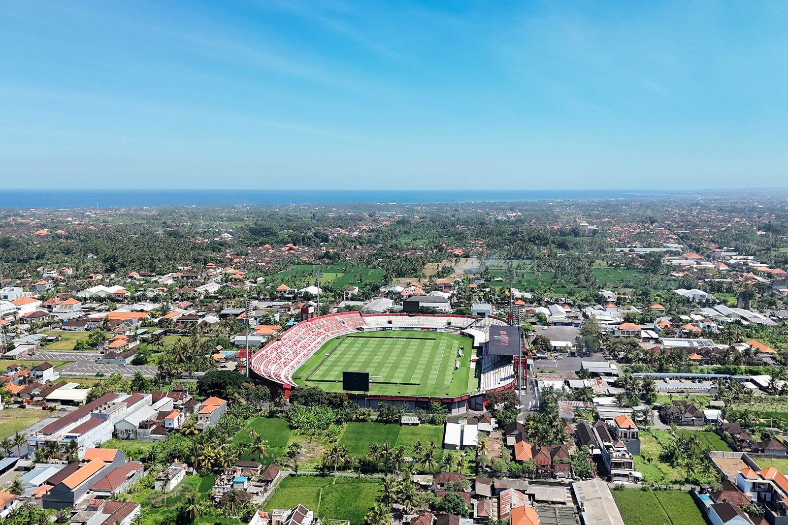 An aerial view of a stadium surrounded by residential buildings and greenery.