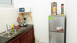 Eine Küche mit einem doppelten Waschbecken, einer Mikrowelle, einem Kühlschrank und einem Regal mit einem Mixer und einer Sprühdose.
