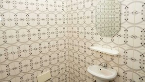 Ein Badezimmer mit gemusterten Fliesen, einem Waschbecken und einem Spiegel.