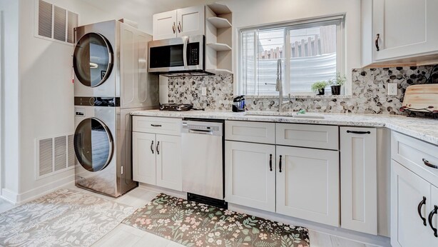 Une cuisine moderne dotée d’appareils électroménagers intégrés, de meubles blancs et d’une fenêtre offrant une belle vue.