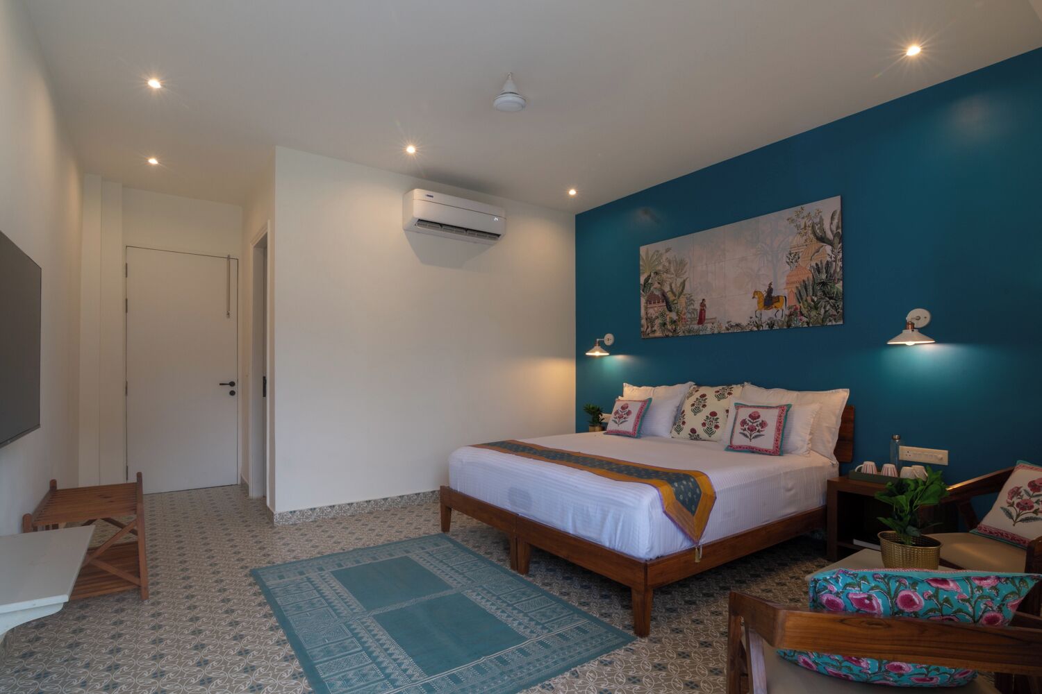 A bedroom with a bed, a desk, a chair, an air conditioner, and a wall-mounted lamp.