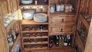 A compact kitchen with wooden cabinetry, wine bottles, and glassware. - Vacation home by the lake - Trausnitz. Nature, peace, relaxation (Trausnitz)