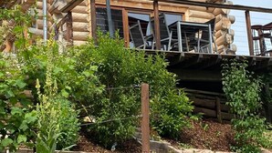 A log cabin with a balcony, wooden deck, and a variety of plants in the garden area. - Vacation home by the lake - Trausnitz. Nature, peace, relaxation (Trausnitz)