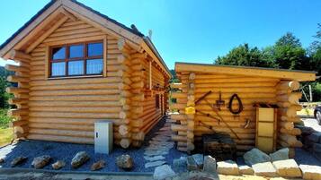 A log cabin with a window and a small attached structure with tools.