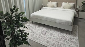 A bedroom with a bed, a nightstand, a lamp, and a potted plant. - 1BR Near metro.Canal  View. Mer. 1709 (Dubai)
