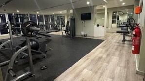 A modern gym with cardio equipment, weightlifting stations, and a fire extinguisher. - 1BR Near metro.Canal  View. Mer. 1709 (Dubai)