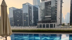 A swimming pool with lounge chairs and a view of modern high-rise buildings. - 1BR Near metro.Canal  View. Mer. 1709 (Dubai)
