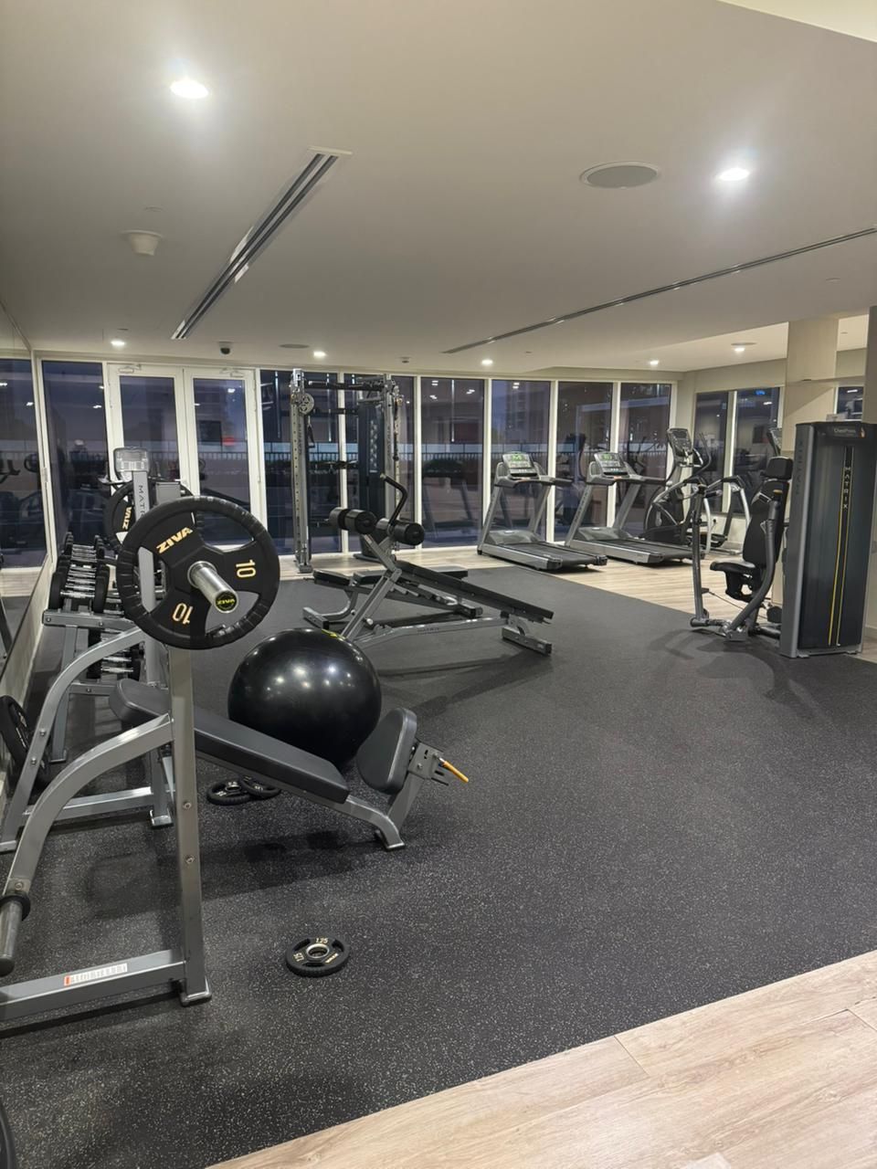 Une salle de sport équipée de machines de cardio, de matériel de musculation et d’un grand ballon d’exercice.
