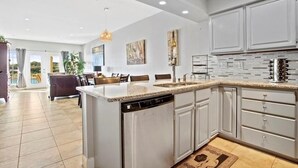 Een moderne keuken met witte kasten, een granieten aanrecht en een vaatwasser.