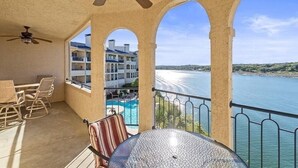 Een balkon met uitzicht op een zwembad en een gebouw in de verte.