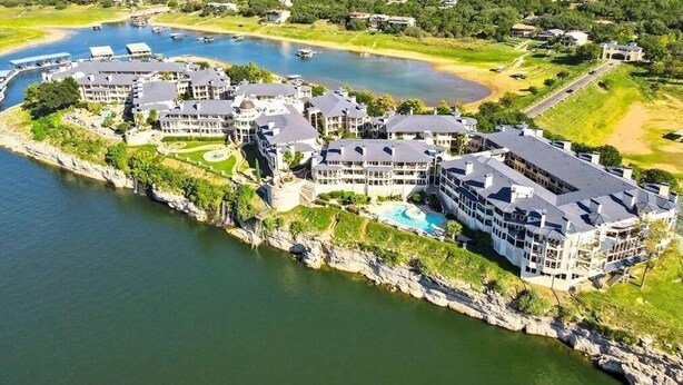 Een kusthotel met meerdere gebouwen, een zwembad en uitzicht op het omliggende landschap en water.