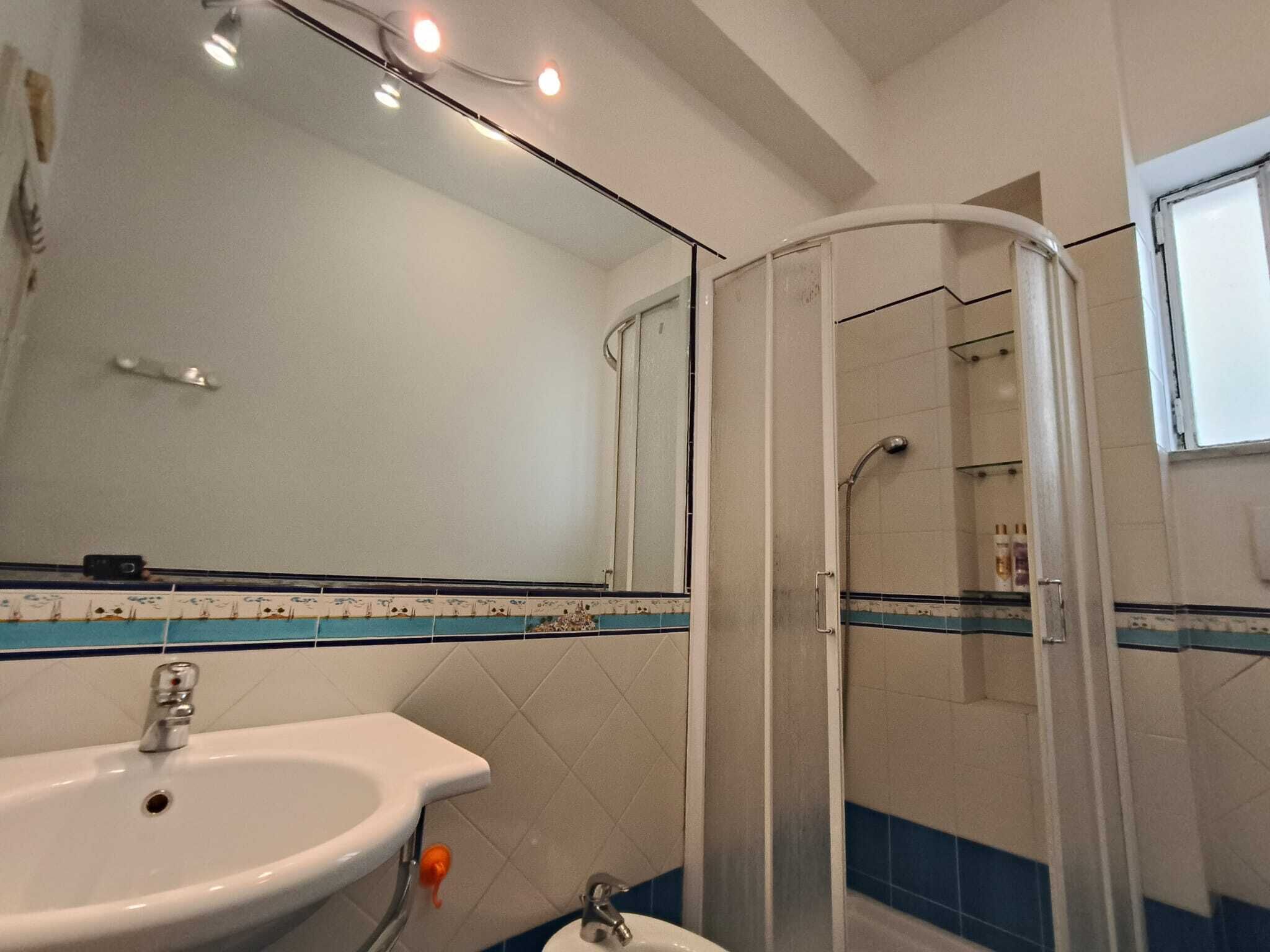 A bathroom with a sink, mirror, shower, and tiled walls.