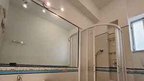Une salle de bain avec un lavabo, un miroir, une douche et des murs carrelés.