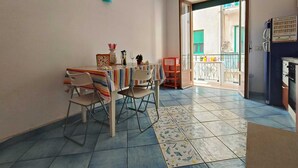 Un coin repas avec une table dressée pour deux personnes, des chaises, une nappe à rayures et un vase décoratif.