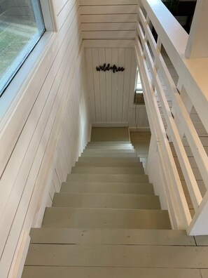 Eine Holztreppe mit weißen Geländern, die zu einer Zwischenebene führt.