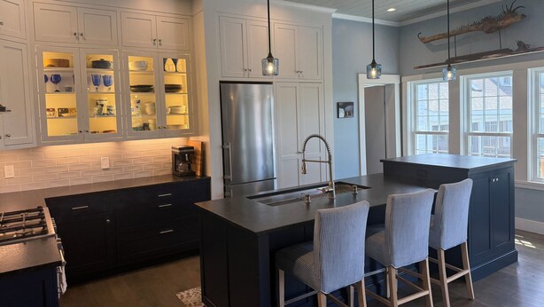 A modern kitchen with a central island, bar stools, and pendant lighting.