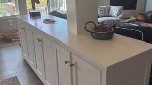 A modern kitchen with white cabinetry, a large island, and a view of the outdoors.