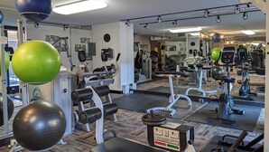 Uma academia com equipamentos de ginástica, espelhos e frases motivacionais nas paredes.