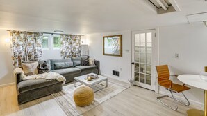 A modern living room with a grey sofa, a round coffee table, and a wicker pouf. - Private Cottage Close to Shopping, Skiing, Swimming, Hiking, Biking and Dining. (Austerlitz)