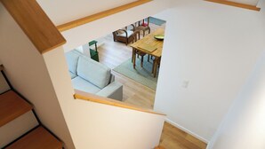 Un escalier menant à une salle à manger avec une table et des chaises en bois.