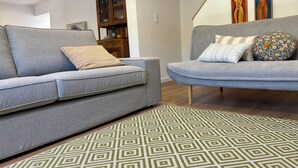 Un salon moderne avec un canapé gris, des coussins à motifs et un tapis à motifs géométriques.