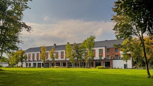 A modern building with a flat roof and brick facade, surrounded by a well-maintained lawn and trees. - Hotel Malbork Centrum Konferencyjne (Malbork)
