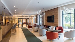 A modern hotel lobby with a bar area, seating, and large windows. - Hotel Malbork Centrum Konferencyjne (Malbork)