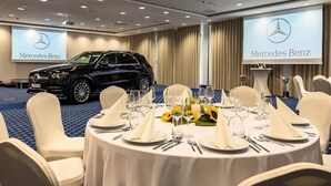 A conference room with a Mercedes-Benz SUV parked in the background, tables set for a meeting with white chairs and a projector screen displaying the Mercedes-Benz logo. - Hotel Malbork Centrum Konferencyjne (Malbork)