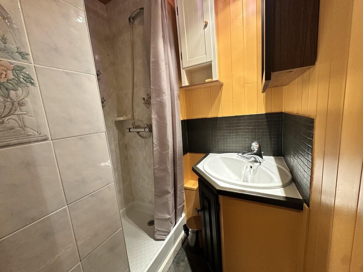 A bathroom with a shower, a sink, and wooden paneling.