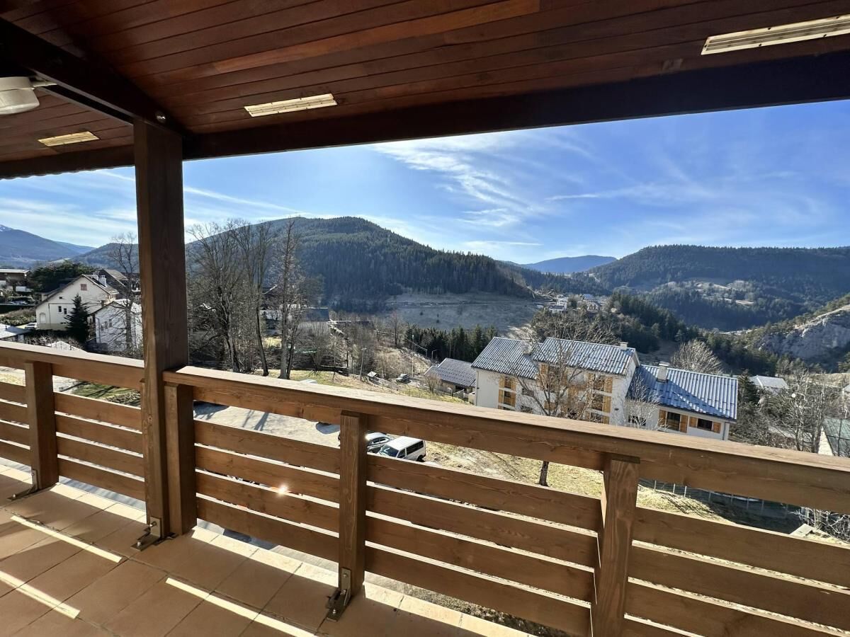 Un balcon en bois offrant une vue sur un paysage montagneux.