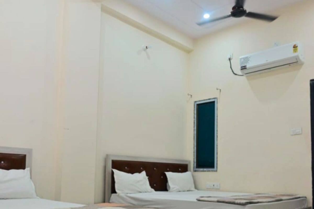Une chambre d’hôtel avec deux lits, un ventilateur de plafond, un appareil de climatisation et un sol carrelé.
