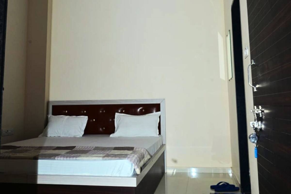 Une chambre à coucher avec un lit, un ventilateur de plafond, un appareil de climatisation et une porte en bois foncé.