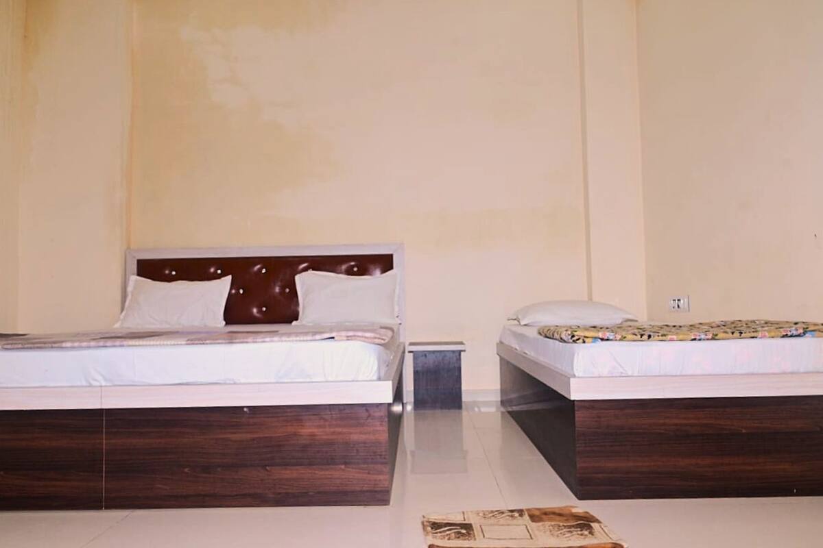 Une chambre d’hôtel avec deux lits, chacun doté d’une tête de lit en bois et de linge de lit blanc.